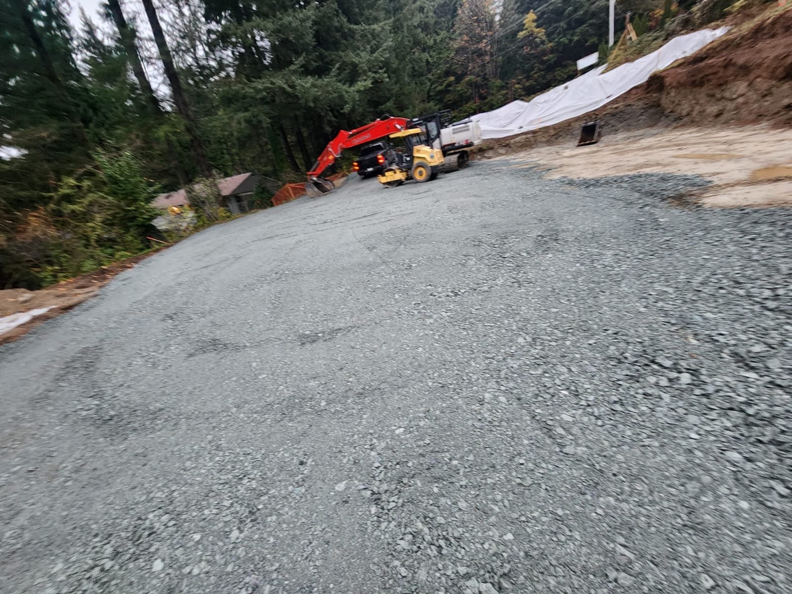 Wide sunset view of graded gravel driveway with equipment