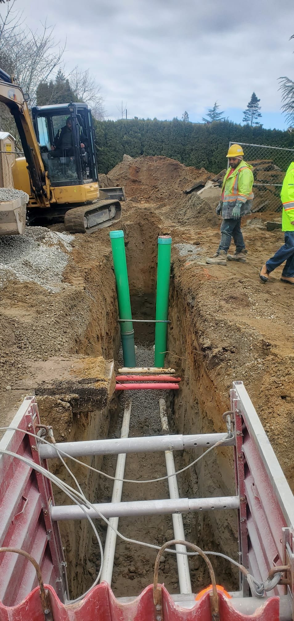 Trench box, riser pipes, and excavator on utility install
